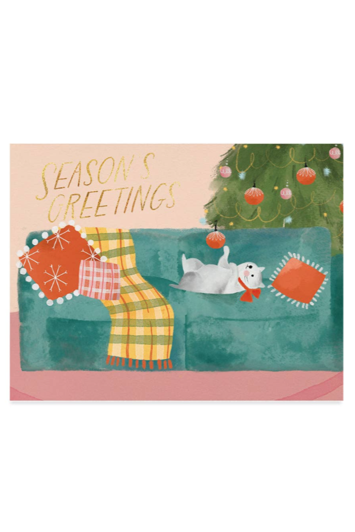 A greeting card featuring a colorful illustration of a kitty with a plaid blanket and a Christmas tree in the background, along with the text 'Seasons' Greetings'.